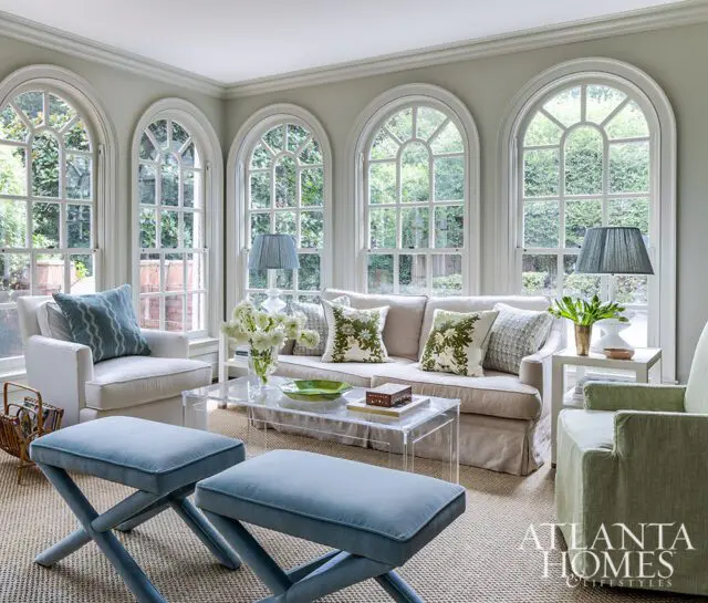 Living room with arched windows, neutral sofa, blue ottomans, and acrylic coffee table.