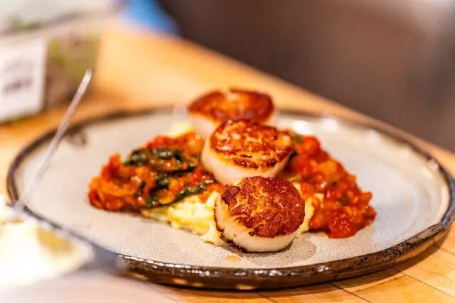 Seared scallops on a bed of polenta with a tomato and spinach sauce