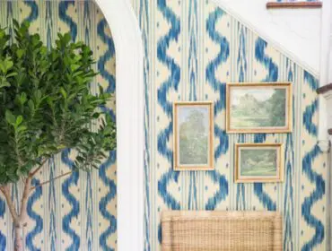 Wicker chair with blue cushion and paisley seat against blue and cream ikat wallpaper