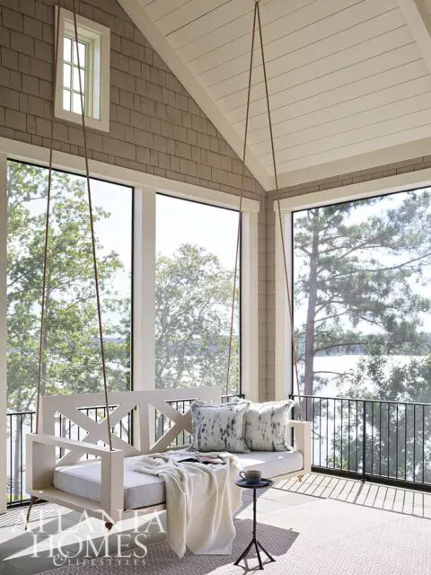 Porch with white swing bed, patterned pillows, and lake view
