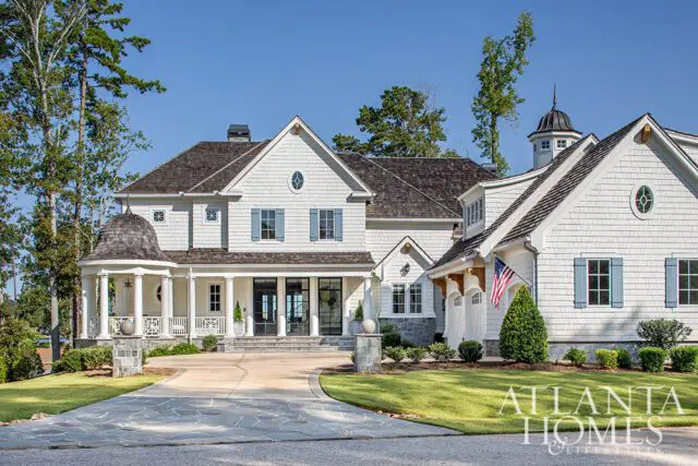 White shingle-sided house with blue shutters and a circular turret porch.