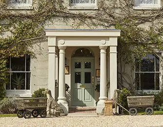Stone house with green door, white columns, and two garden carts