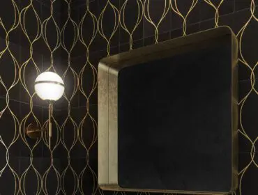 Powder room with black tile and gold art deco pattern, gold mirror, and marble vanity.