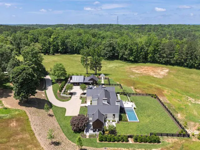 Modern farmhouse with dark roof, white siding, pool, and fenced yard