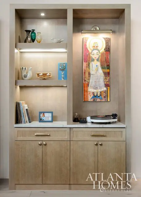 Built-in shelving with artwork, books, vases, and a record player.