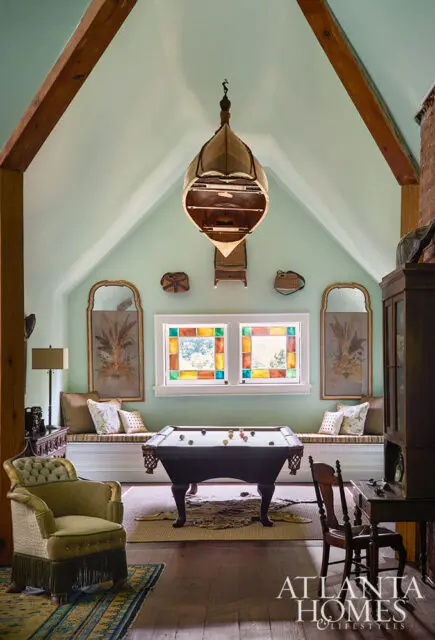Billiard room with mint green walls, stained glass windows, and a unique hanging light fixture.