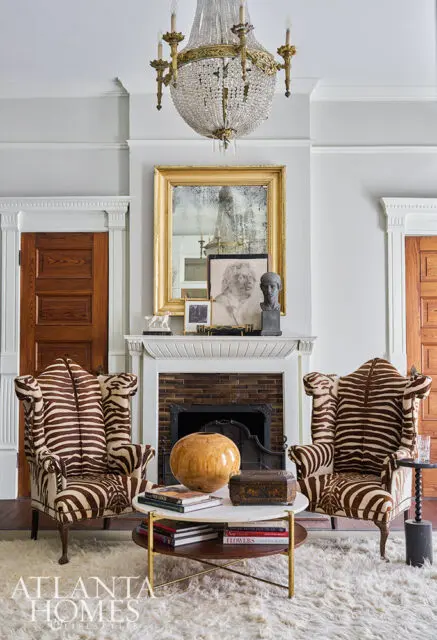 Living room with two zebra-print armchairs, a marble coffee table, and a crystal chandelier.