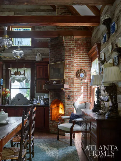 Rustic kitchen with brick fireplace, wooden beams, and antique furniture.