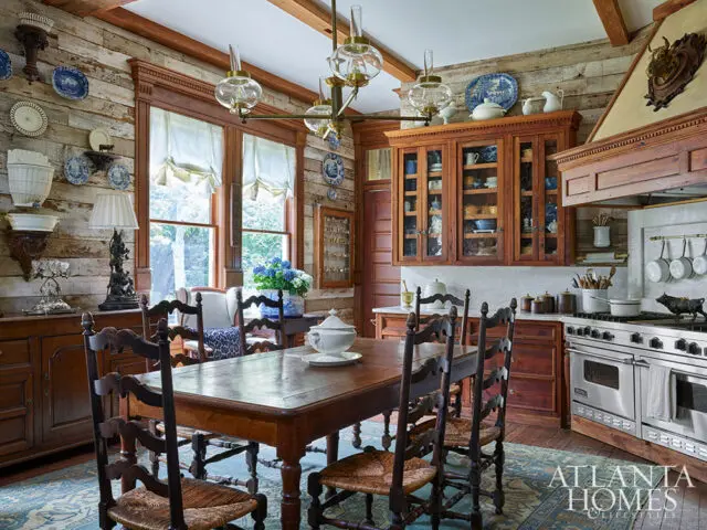 Rustic dining room with wood plank walls, wooden table and chairs, and a large stainless steel