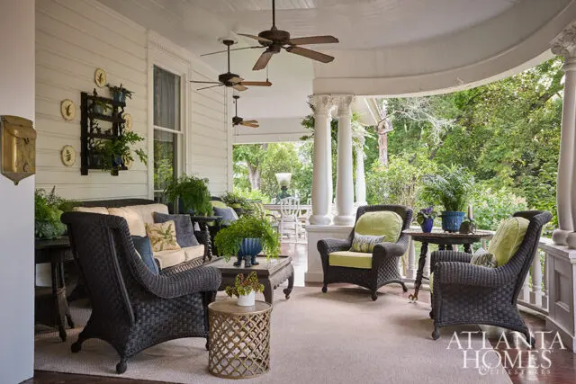 Wicker furniture on a covered porch with ceiling fans and lush greenery