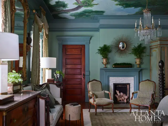 Green room with fireplace, two patterned chairs, and painted ceiling mural