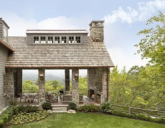 Stone house with covered porch, outdoor fireplace, and mountain view