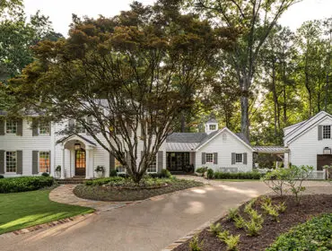White clapboard house with dark shutters and a stone pathway