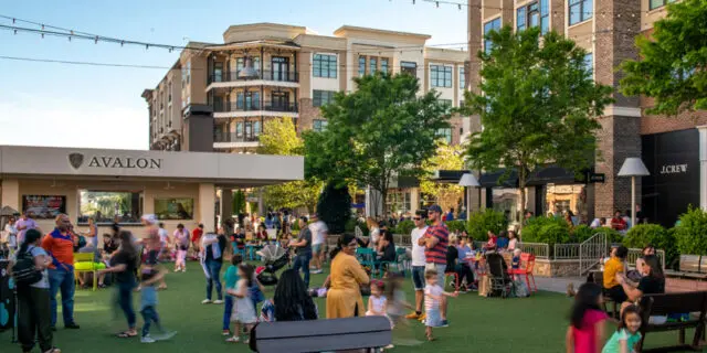 Avalon building with people gathered on green lawn, J. Crew store visible
