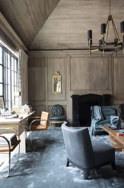 Wood paneled room with desk, fireplace, and seating.