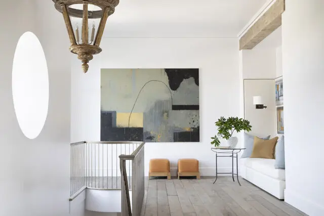 Hallway with abstract art, wooden chandelier, and built-in bench seating.