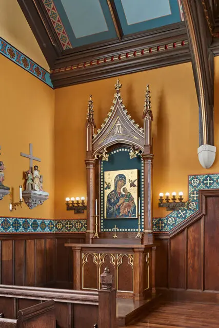 Church interior with ornate altar featuring an icon of Mary and Jesus, wood paneling, and