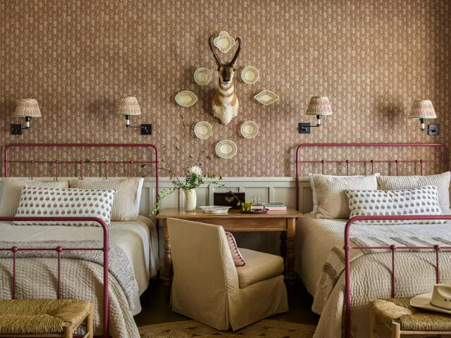 Guest bedroom with two twin beds, patterned wallpaper, and taxidermy antelope head
