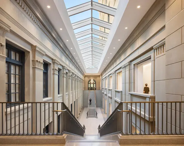 Interior atrium with stone walls, glass ceiling, and grand staircase