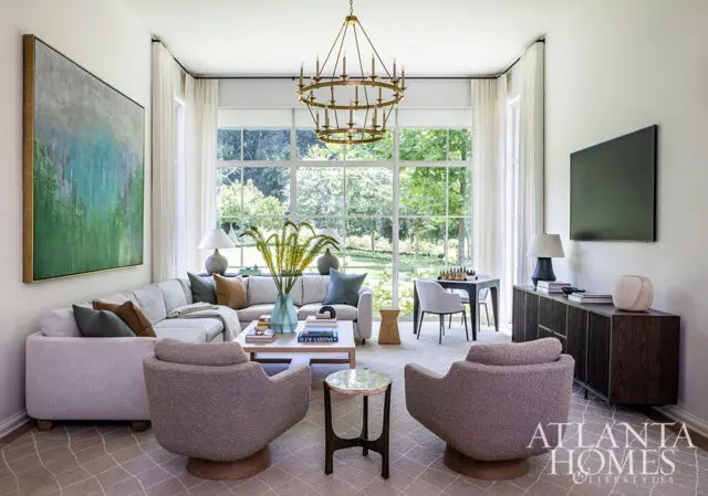 Living room with sectional sofa, two swivel chairs, abstract art, and large windows overlooking a