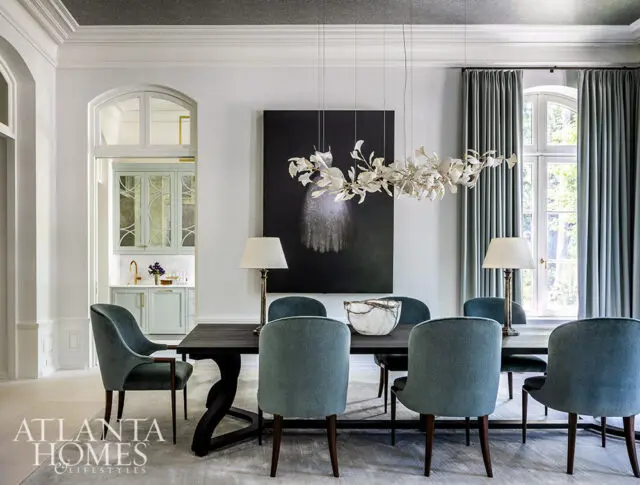 Dining room with teal upholstered chairs, dark wood table, and abstract art.