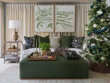 Living room with green ottoman, white sofa, and Christmas tree decorated with green ornaments and