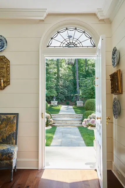 Interior view through an open door to a garden path with stone steps and lush greenery.