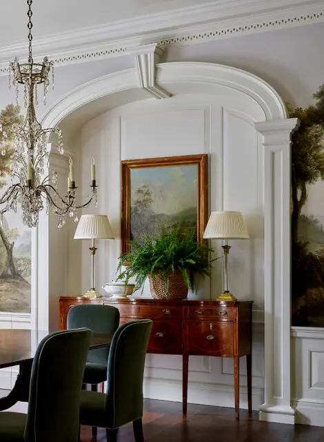 Dining room with dark wood buffet, landscape painting, and crystal chandelier