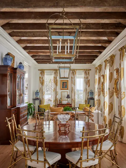 Dining room with dark wood table, gold bamboo chairs, and exposed wooden beams.