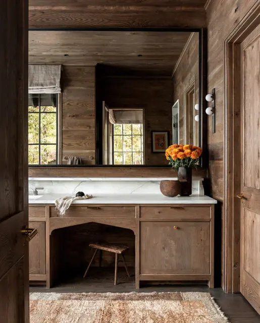 Wood paneled bathroom with vanity, marble countertop, and orange flowers.