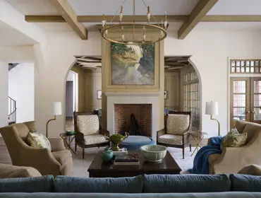 Living room with fireplace, arched doorways, and seating arranged around a coffee table.