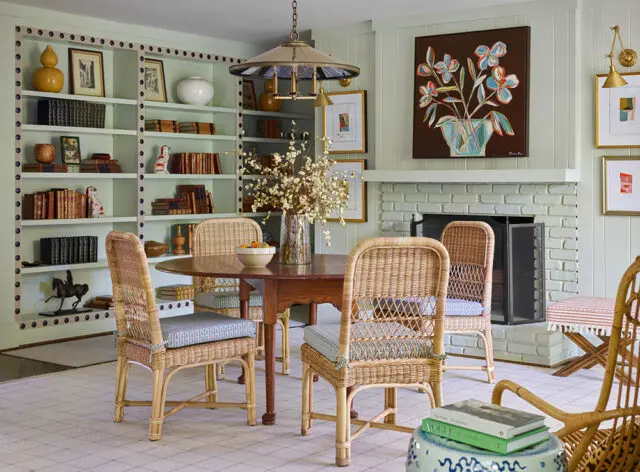 Light green dining room with wicker chairs, a wooden table, and built-in bookshelves.