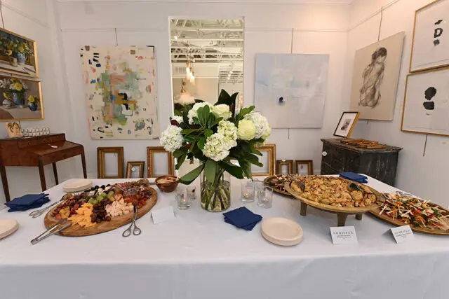 Table with cheese board, appetizers, floral arrangement, and artwork on wall