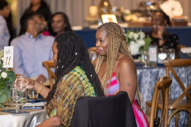 Table 11 with floral arrangement and two women seated at a formal event.