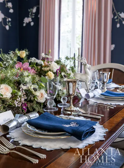Dining table set with blue napkins, floral centerpiece, and deer figurine.