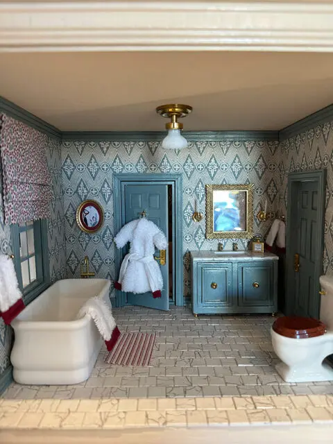 Dollhouse bathroom with white tub, blue vanity, and patterned wallpaper