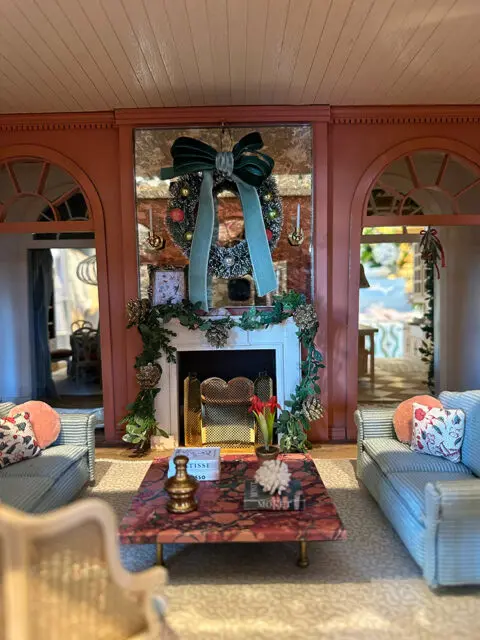 Dollhouse living room with blue striped sofas, coral pillows, and a marble coffee table.