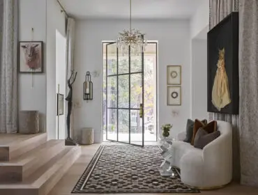 Entryway with wood stairs, abstract art, sculpture, and curved sofa
