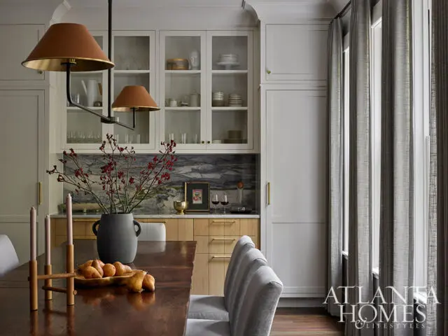 Dining room with dark wood table, gray chairs, and built-in white cabinetry with glass doors.