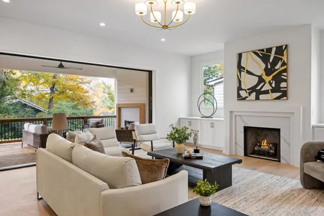 Living room with white sofas, dark wood coffee table, fireplace, and large sliding doors to a deck.
