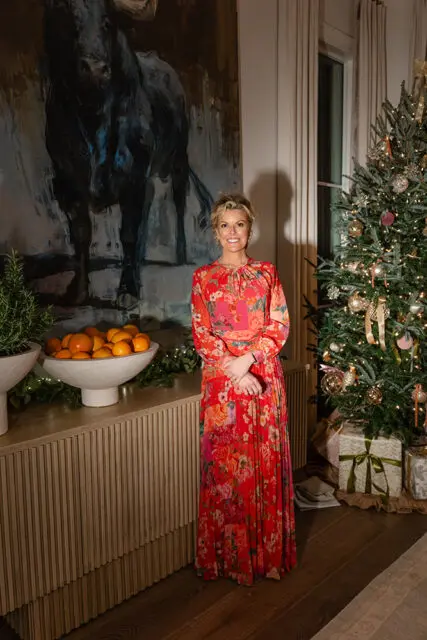 Woman in floral dress standing by Christmas tree and large bull painting