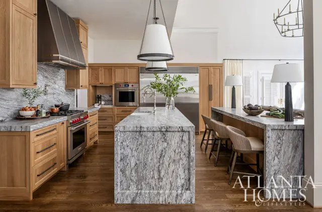 Kitchen with light wood cabinetry, marble countertops, and a large island.