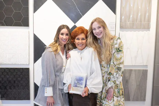 Three women holding an award in front of tile samples.