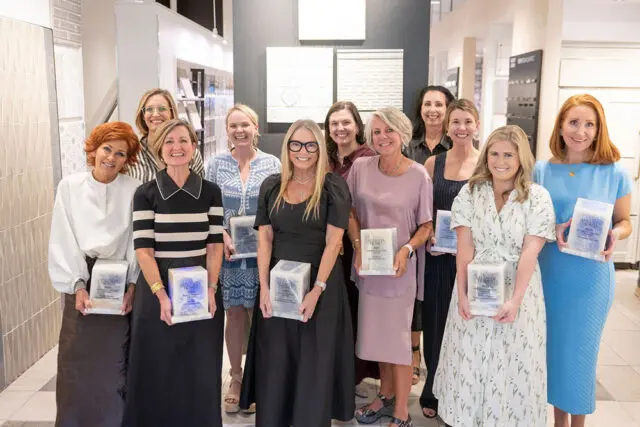 Group of women holding awards in a showroom with tile displays