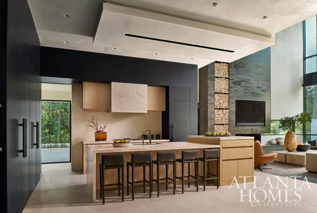 Modern kitchen with wood cabinetry, marble island, and stacked wood fireplace