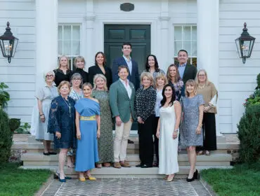 Group of people posing on the steps of a white house