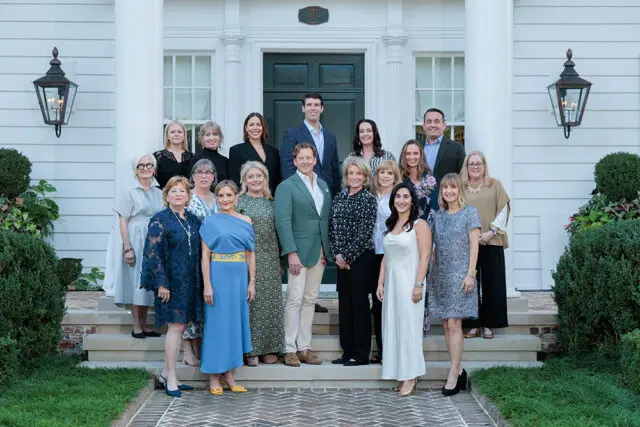 Group of people posing on the steps of a white house