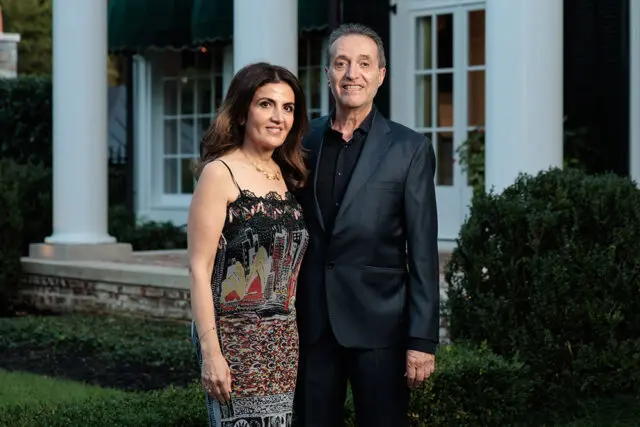Couple standing outside a white house with columns.