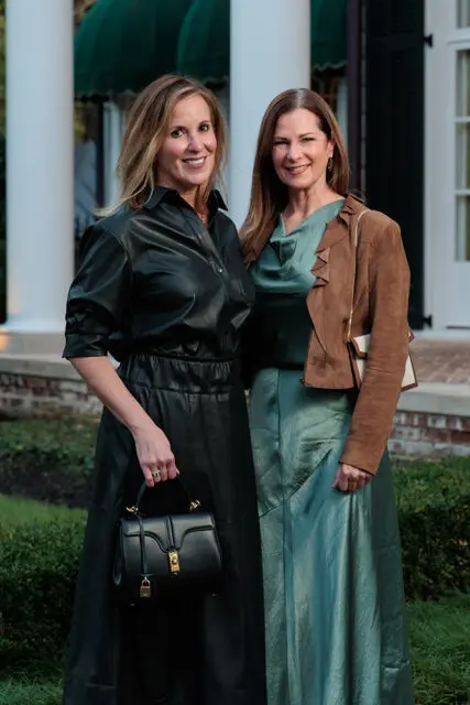 Two women posing outdoors in front of a white building with columns.