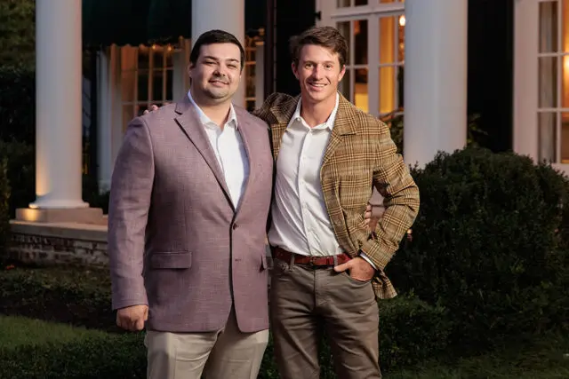 Two men standing outside a white house with columns.